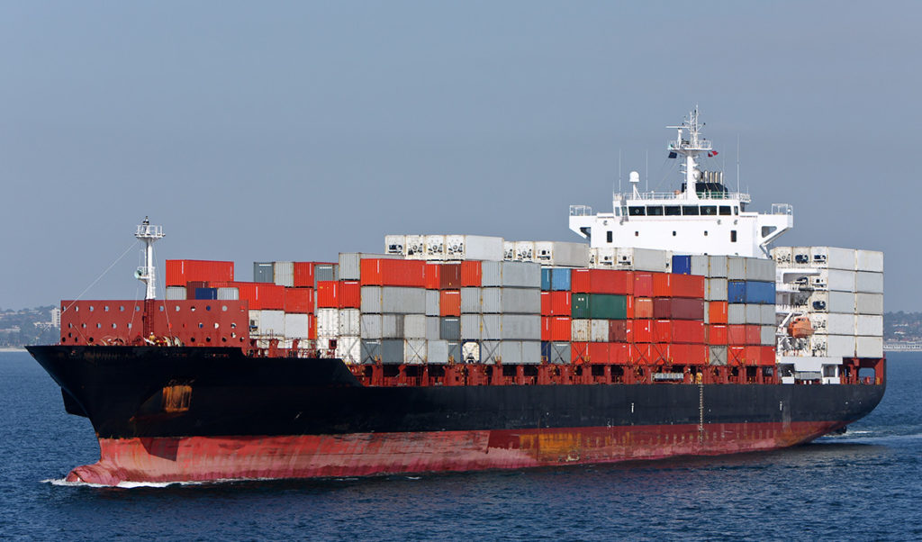 An unidentified ship with containers stacked high on deck.