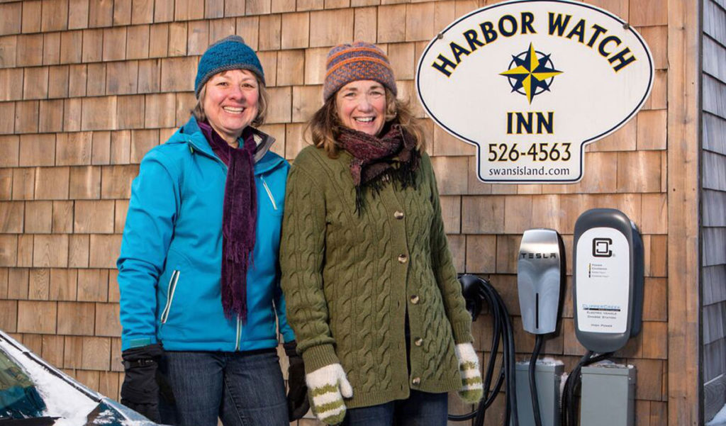 Harbor Watch Inn owner Colleen Hyland (right) looks on as Janice Kenyon of Southwest Harbor uses the inn’s new charging station with her all-electric 2015 Nissan Leaf.