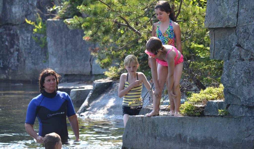 Tracie Martin instructs a group of middle level students about how to don a life jacket while in the water at Lawson's Quarry