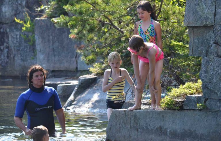 Tracie Martin instructs a group of middle level students about how to don a life jacket while in the water at Lawson's Quarry