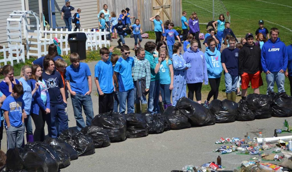 Vinalhaven school students and staff start to congregate outside around the trash collage and spend some time considering all the trash they collected.