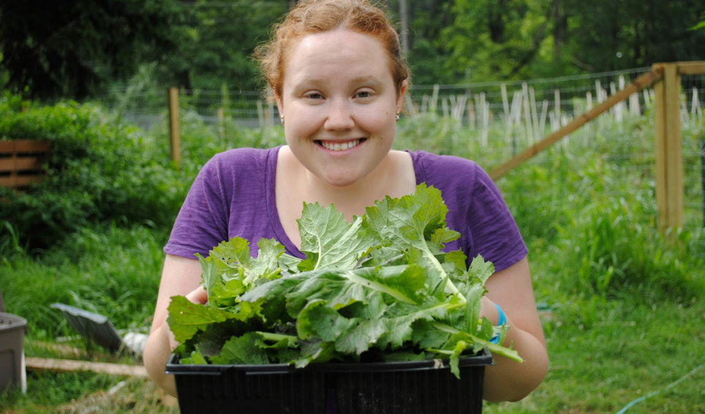 A WWOOFer at a farm in Connecticut poses with the bok choy she grew.
