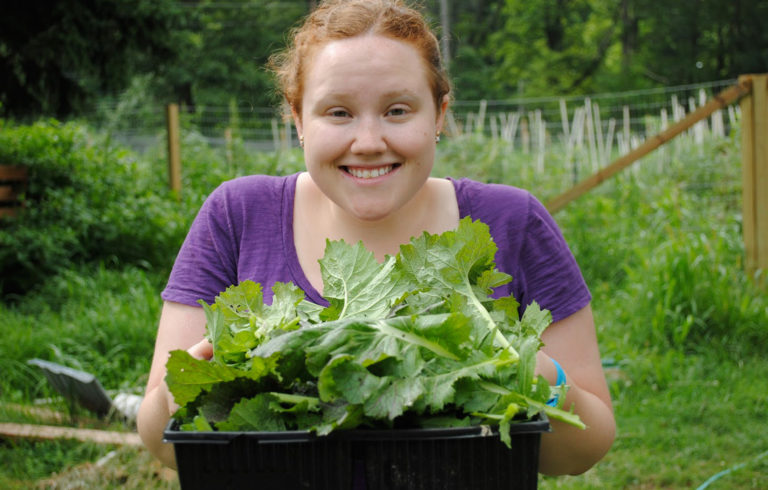 A WWOOFer at a farm in Connecticut poses with the bok choy she grew.