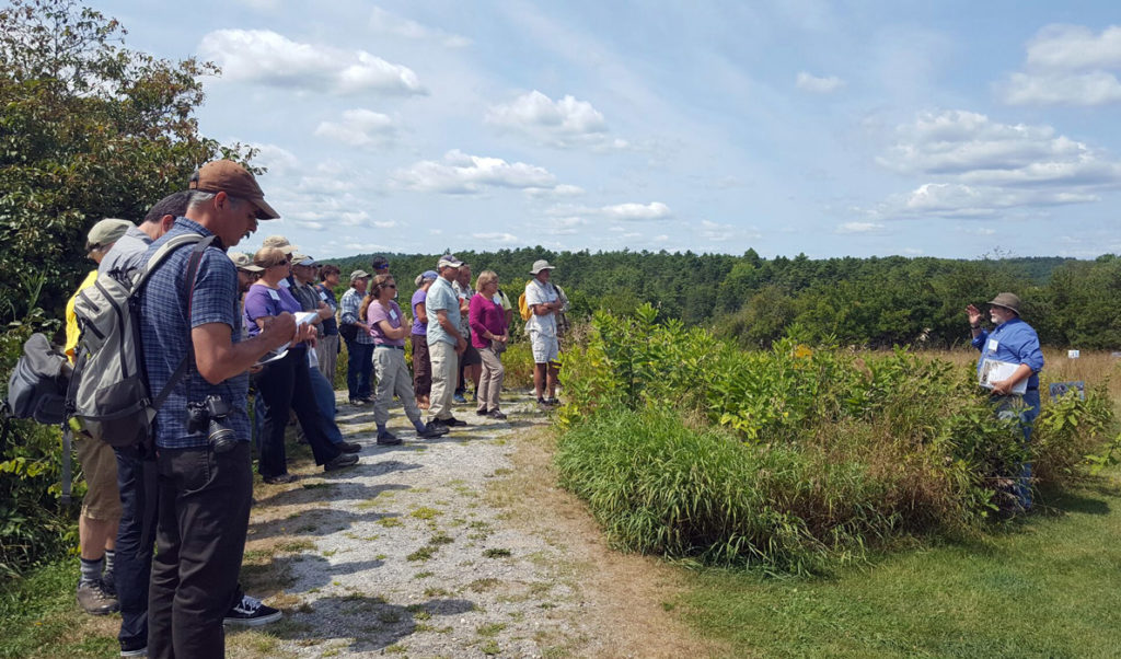 Conference attendees at Whaleback Shell Midden Historic Site in Damariscotta listen to Arthur Spiess