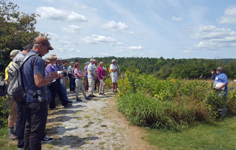 Conference attendees at Whaleback Shell Midden Historic Site in Damariscotta listen to Arthur Spiess