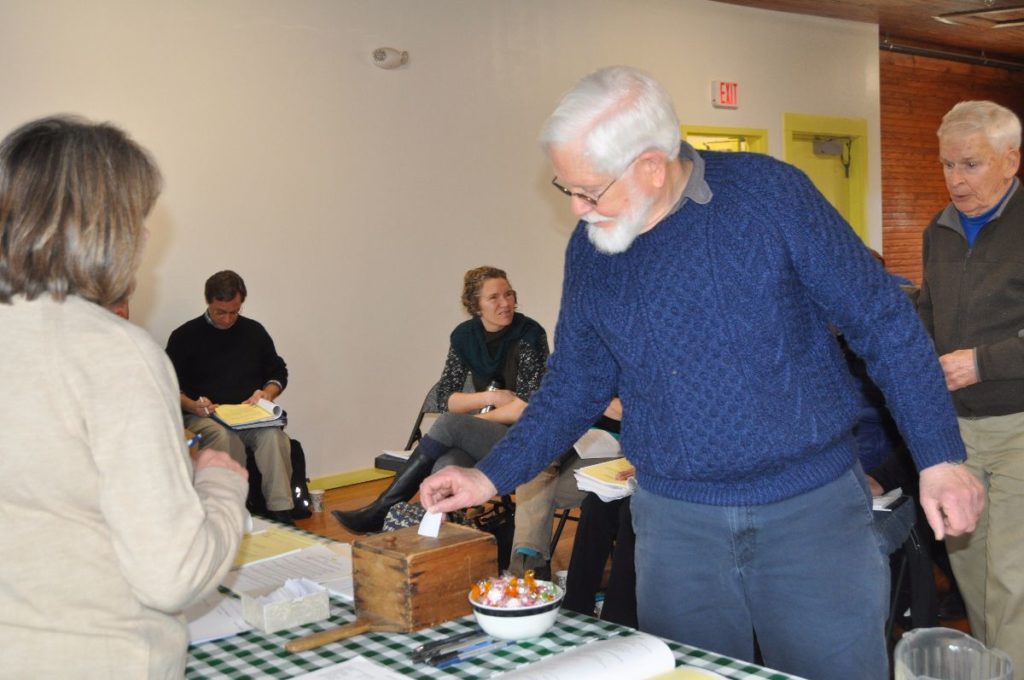 Skip Stevens votes on a warrant article at the Cranberry Isles town meeting at Longfellow School on Saturday.