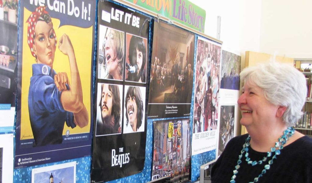 Donna Damon poses in front of a bulletin board in her classroom that reflects her life.