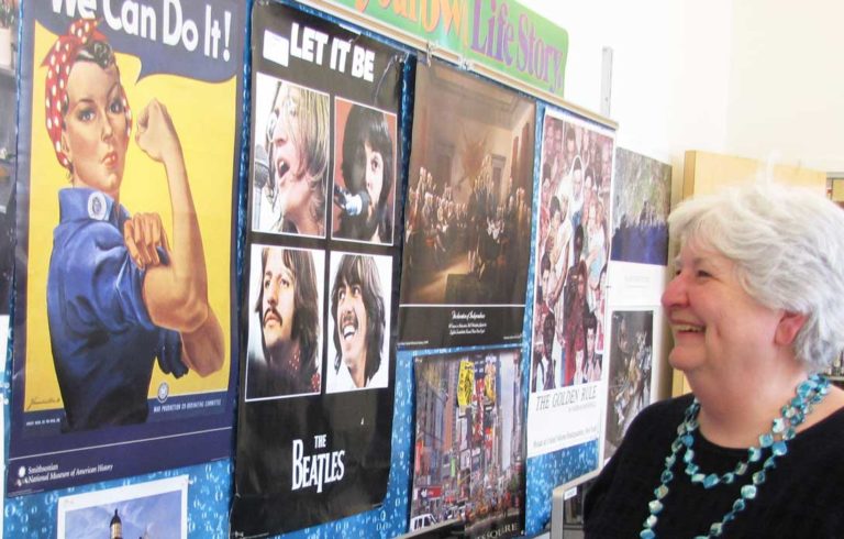 Donna Damon poses in front of a bulletin board in her classroom that reflects her life.