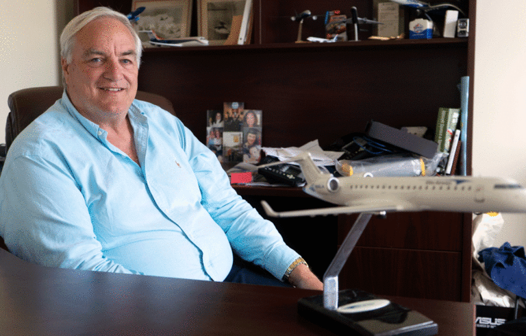 John Pearsall poses in the Portland offices of Elite Airways with a model of one of the aircraft his company flies.