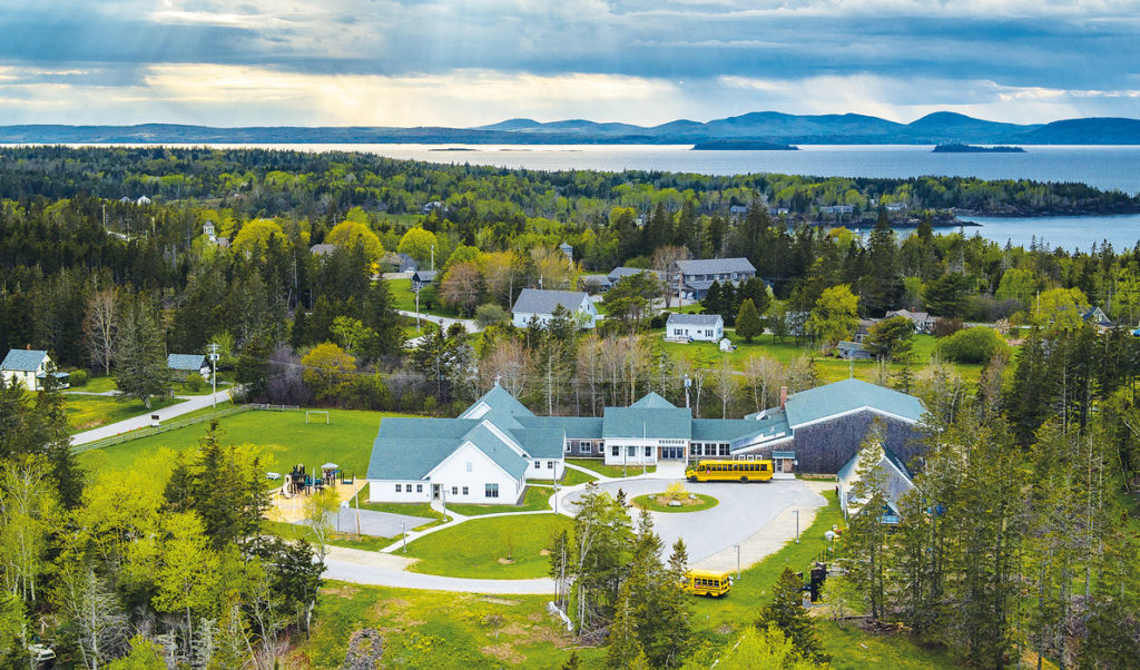 An aerial photo shows the North Haven Community School with the Camden hills on the horizon.