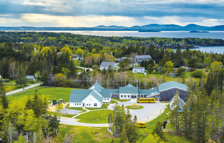 An aerial photo shows the North Haven Community School with the Camden hills on the horizon.