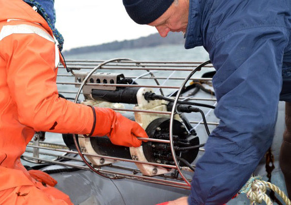 Susie Arnold and Paul Dobbins lower a CO2 sensor into the water