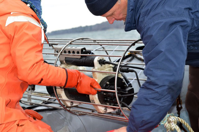 Susie Arnold and Paul Dobbins lower a CO2 sensor into the water