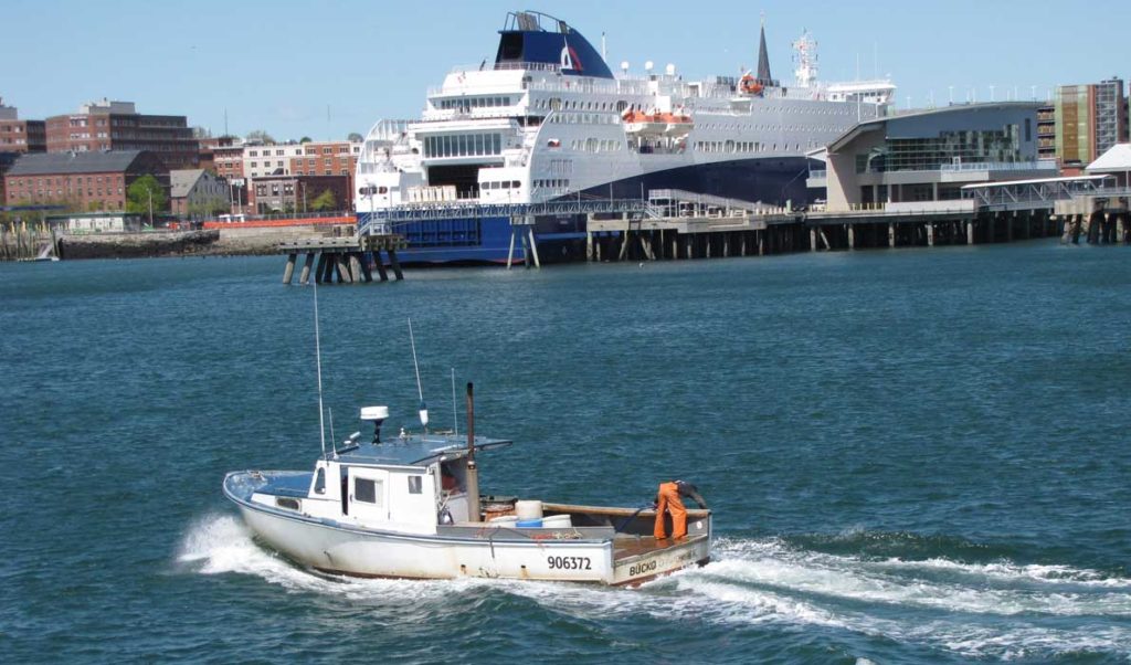 A lobster boat cruises through Portland Harbor with the Nova Star