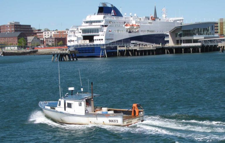 A lobster boat cruises through Portland Harbor with the Nova Star