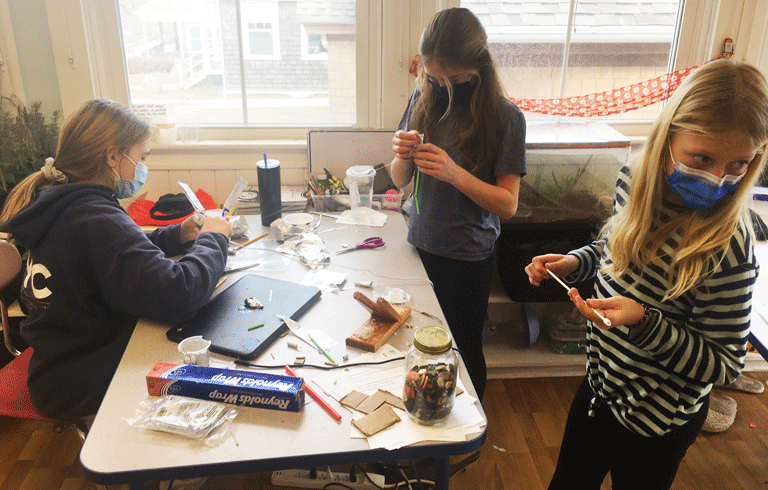 From left are seventh graders Lola Gahan and Hannah Frothingham and fifth grader Lucy Lombard of the Cuttyhunk School. The students built satellite models after the virtual NASA field trip. PHOTO: MICHELLE CARVALHO