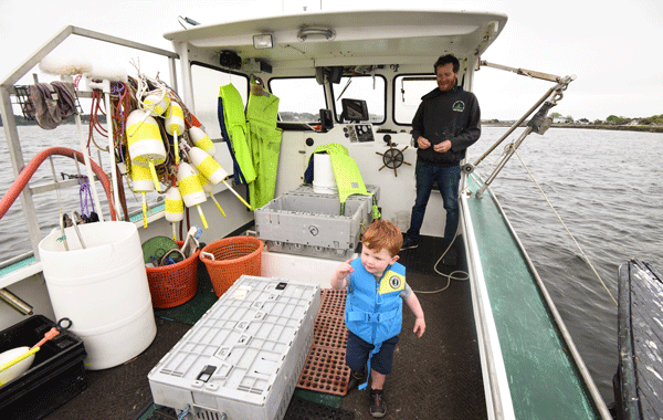 DeBery shows two-year-old Kieran Park what running a lobster boat is all about.