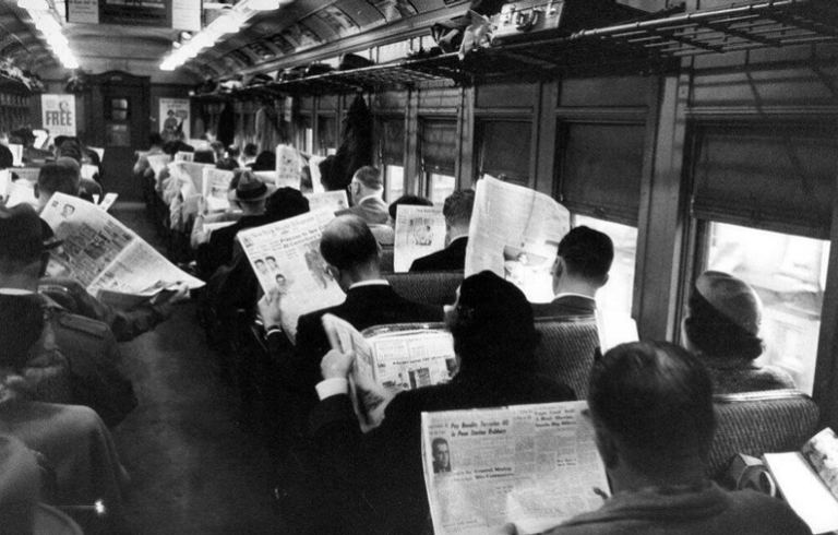 Reading newspapers on a train.