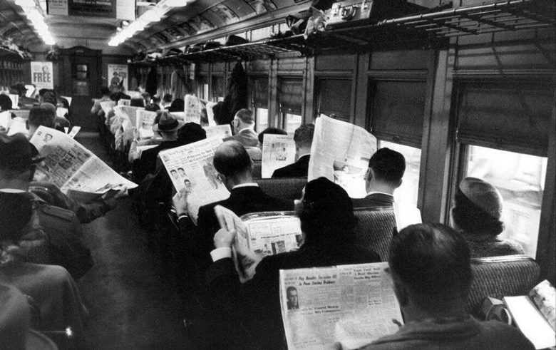 Reading newspapers on a train.