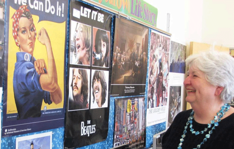 Donna Damon poses in front of a bulletin board in her classroom just before she retired. FILE PHOTO: TOM GROENINGa