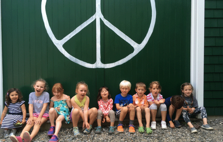 Children pose in front of Waterman's peace sign.