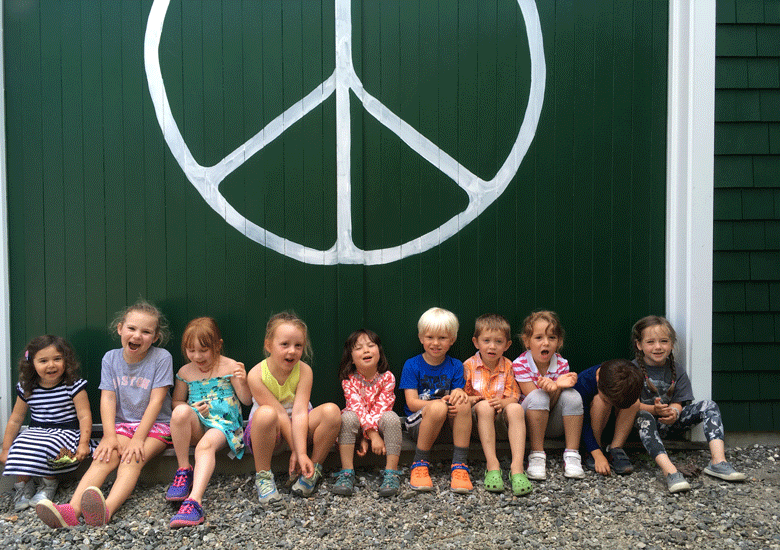 Children pose in front of Waterman's peace sign.