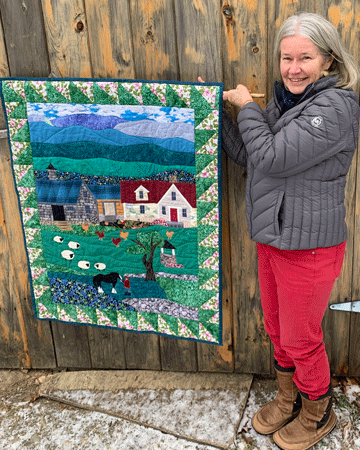 Nora Flanagan poses with one of her quilts.