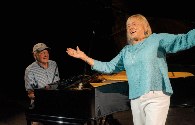 Phil Crossman sits at the piano at Waterman's Community Center on North Haven as Gov. Janet Mills, vacationing on the island, sings.