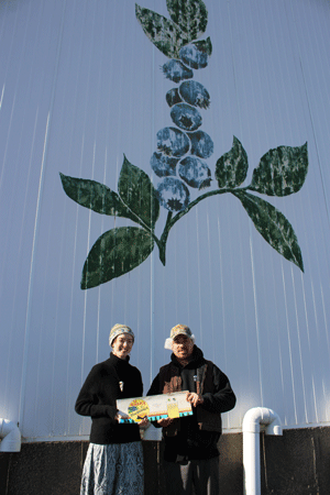 Simeon Allen and Katie Liberman, the Island Institute Fellow, pose in front of W.R. Allen’s wild blueberry processing plant holding some original canning labels from the company’s former canning operation. PHOTO: COURTESY KAYSIE LOGAN