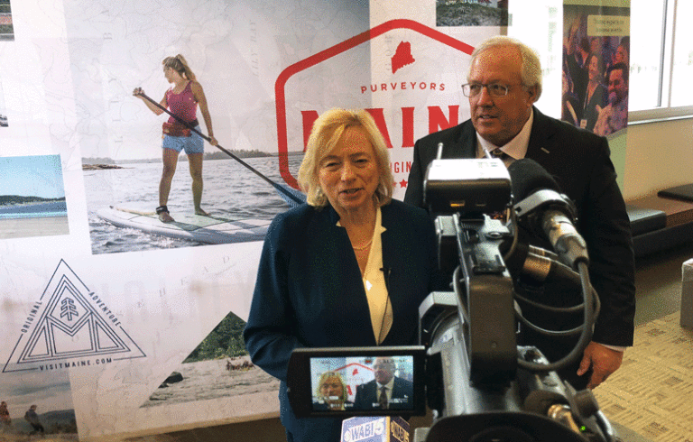 Gov. Janet Mill, left, poses with Paul Coulombe in front of TV cameras at the Governor’s Tourism Conference in Bangor on March 28. Coulombe was honored with the Governor’s Award for Excellence in Tourism for his philanthropy and commercial development work in Boothbay Harbor. PHOTO: TOM GROENING
