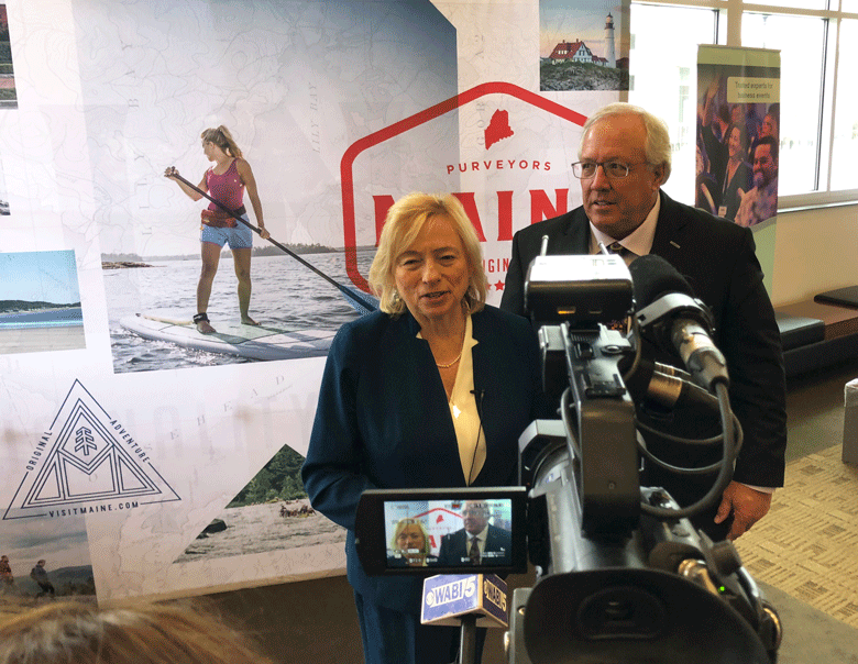 Gov. Janet Mill, left, poses with Paul Coulombe in front of TV cameras at the Governor’s Tourism Conference in Bangor on March 28. Coulombe was honored with the Governor’s Award for Excellence in Tourism for his philanthropy and commercial development work in Boothbay Harbor. PHOTO: TOM GROENING