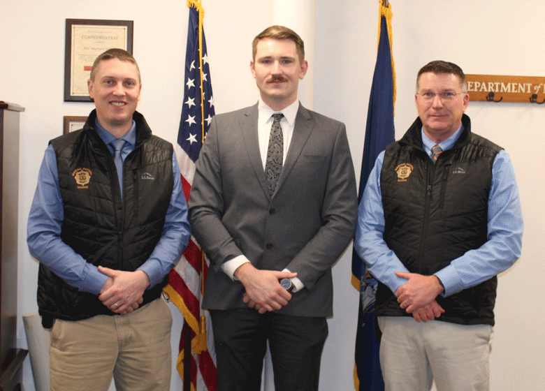 New Maine Marine Patrol Officer Ben Wiant, center, with Col. Matthew Talbot, left, and Department of Marine Resources Commissioner Patrick Keliher.