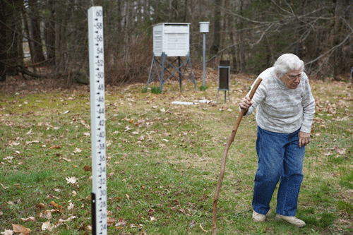 Cole walks by the measuring stick she uses to record snowfall.