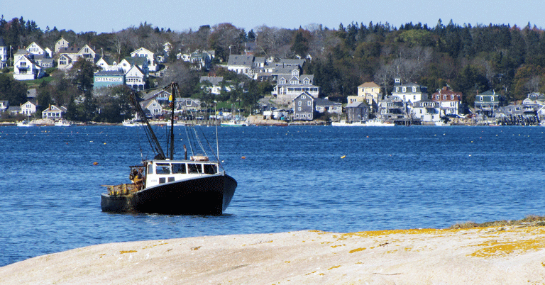 A fishing boat hauls traps with Stonington in the background. FILE PHOTO: TOM GROENING
