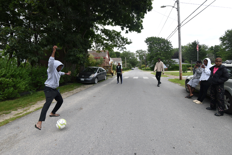 Chadai Gatembo playing soccer in the street with friends.