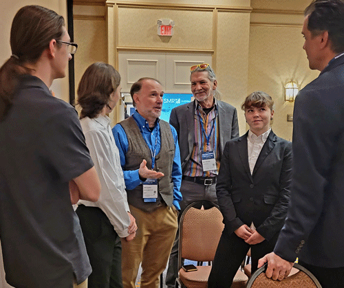 Jim Lenke, a science teacher at Machias Memorial High School, center, stands with his students and Machias Town Manager Bill Kitchen, speaking to NASA's Mike Kincaid (far right). Students from several schools presented research at the first Maine State Space Conference. PHOTO: SARAH CRAIGHEAD DEDMON