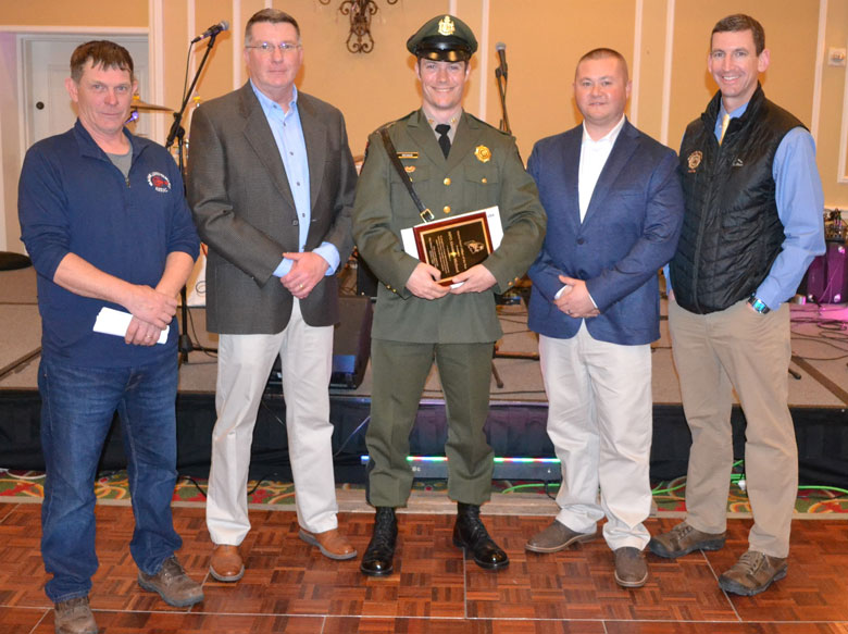 Maine Marine Patrol Officer Alex Michaud, center, receives the 2024 Maine Lobstermen’s Association Officer of the Year Award during the Fishermen’s Forum. From left are and MLA board president Kristan Porter Department of Marine Resources Commissioner Patrick Keliher, from left), Sgt. Matthew Wyman, and Major Rob Beal.