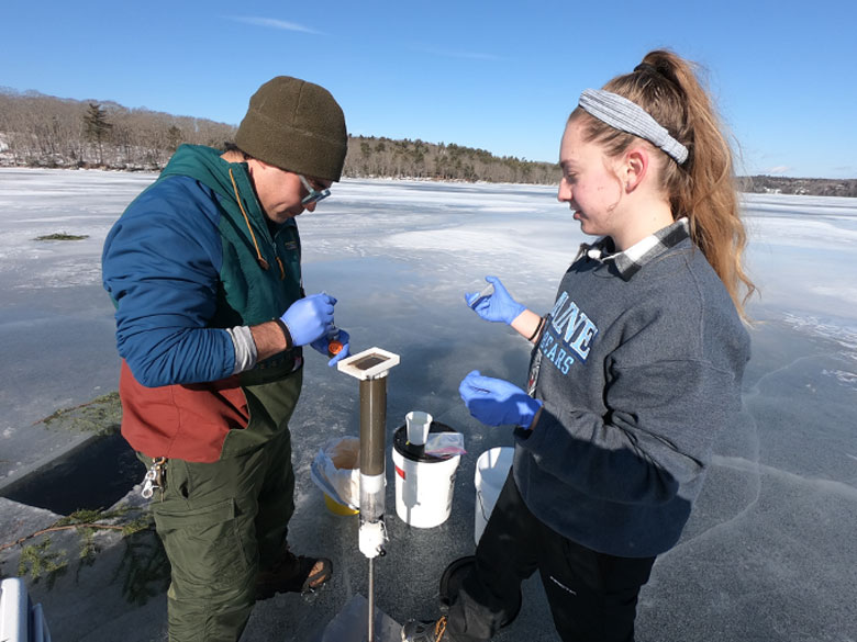 UMaine graduate students Grayson Hutson and Julia Sunnarborg collecting an eDNA sample through the ice at Walker Pond. Grayson and Julia and colleagues at the University of Maine and University of Southern Maine are using eDNA to study migration patterns of alewives as they move between saltwater and freshwater to understant their affects on lake and estuary ecosystems, especially in cases where dams are being removed to increase fish passage. They are even mining the lake sediments for ancient eDNA to understand what fish populations might have looked like in the past.