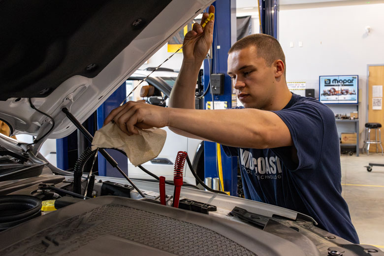 Knasic Byer checks fluid on a truck in the automotive shop.