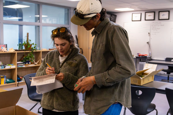 Hazel Crabtree, left, and Eben Wieselogel inventory gear after a trip in the outdoor recreation program.