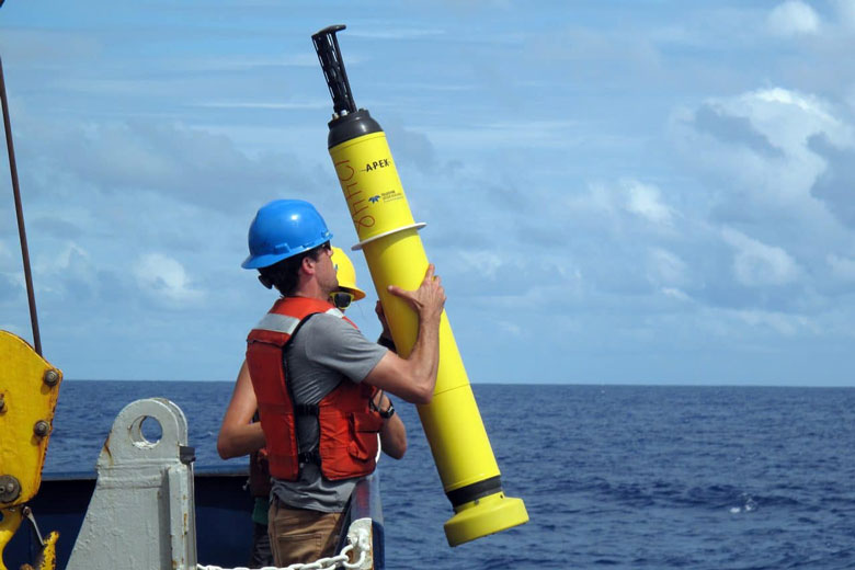 Staff with the Woods Hole Oceanographic Institute prepare to launch a drifter buoy.