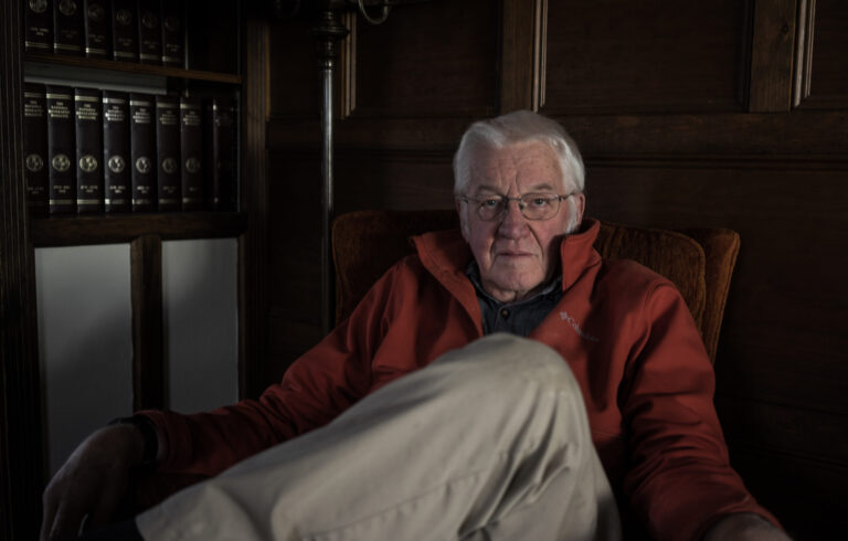 man looking directly at camera sitting in dimly lit room